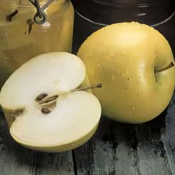 Yellow apples, whole and sliced on a table.