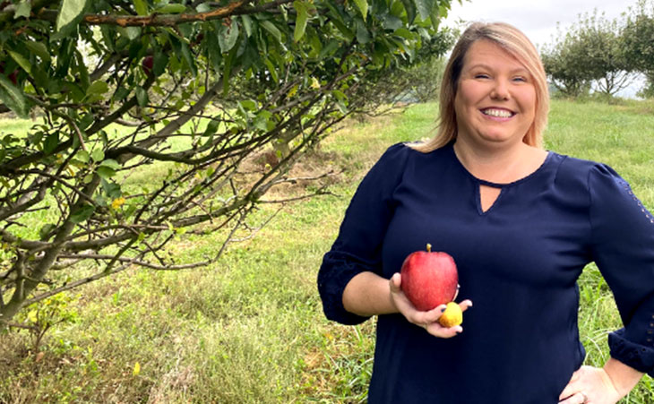 Photo of Tabitha Rardon, Stark Brothers customer service manager, holding an apple in an orchard