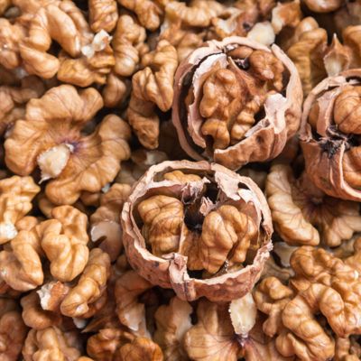 Walnut cracked open on top of shelled walnuts