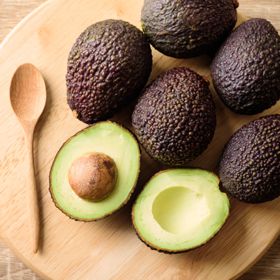 Hass Avocados on cutting board, one cut open