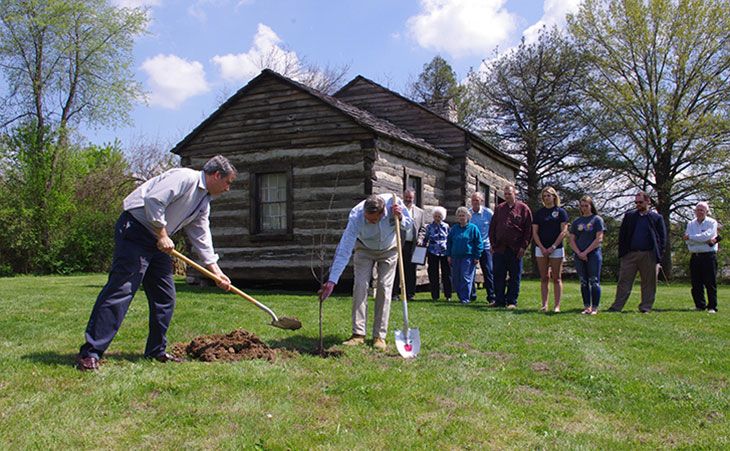 Planting a tree in front of James Stark cabin