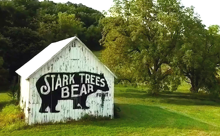 Photo of a barn with the Stark Brothers bear logo with text Stark trees bear fruit